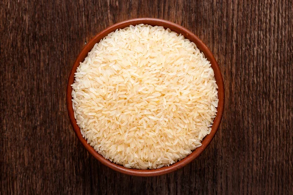 Yukarıdan koyu renkli ahşap izole çiğ çiğ basmati pirinç Rustik Seramik kase