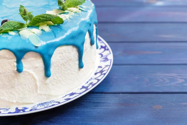 Cake decorated with blue cream, mint and blueberries.