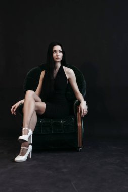 İnce esmer kadın kanepede oturuyor. Yeni yıl arifesi, karanlık arka plan..