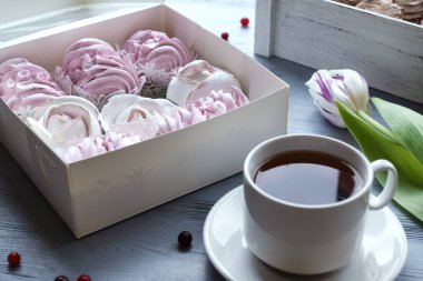 Bahar kutlaması yatıyordu. Kahveli beyaz fincan, pembe laleler ve şekerleme. Tatil geçmişi. Tebrik kartı.