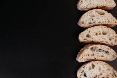 Siyah arka planda dilimlenmiş ciabatta ekmeği. İtalyan beyaz ekmeği. Kopyalama alanı olan üst görünüm.