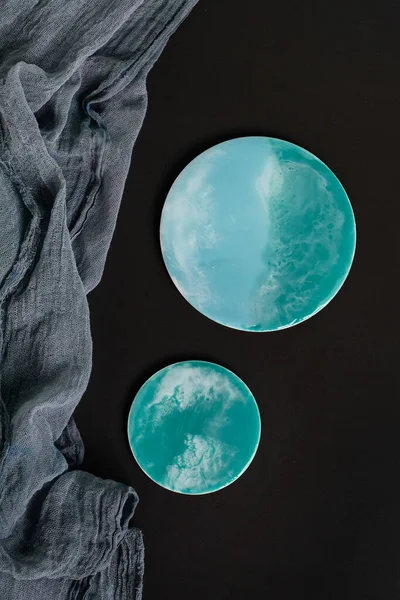 Epoxy resin turquoise on black background round plates. Resin art. Top view, flat lay.