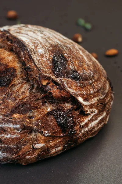 Fresh Sourdough Bread on black background. Fresh baked homemade rye bread, top view. Bread with nuts and candied fruits.