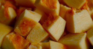 Canlı turuncu renkler ve sulu dokular gösteren taze balkabağı küplerinin yakın çekimi. Sonbahar yemekleri, sağlıklı tarifler ve mevsimlik sebze hazırlığı için ideal.