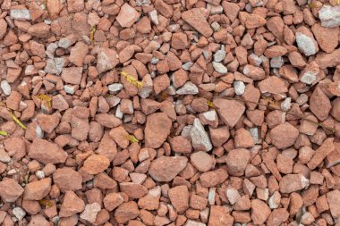 Kırık kırmızı tuğla döküntü dokusu. İnşaat enkazından kırılan taş ve çakıl yığınları. Tırtıklı taş parçalarının soyut zemin yüzey deseni.
