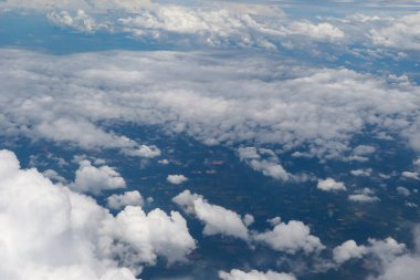 Mavi okyanus ve karaya dağılmış beyaz kümülüs bulutlarının çarpıcı hava manzarası doğal güzellik ve sükunet sergiliyor..