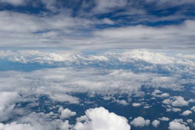 Bulutların üzerinden bir manzara, üzerinde ince bulutlar ile mavi gökyüzüne yayılmış beyaz kabarık bulutlar.