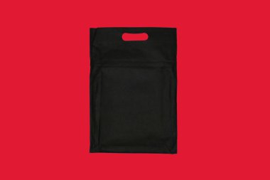 Sade kırmızı arka planı olan siyah bir çanta. Alışveriş için ideal ve günlük taşınma.