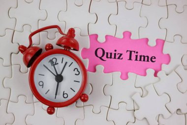 Kırmızı alarm saati, 'Sınav Zamanı' başlıklı pembe süslemeli beyaz yapboz parçaları arasında yer alır, eğitim, çalışma ve oyun temelli aktivitelerde odak, öğrenme ve zamanlanmış zorlukları sembolize eder.