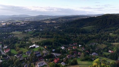 Bu çarpıcı manzaranın tadını çıkarın. Manzaralı tepeler ve büyüleyici evler, doğanın güzelliğini ve sükunetini vurguluyor.