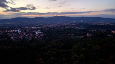 Gün batımında yemyeşil tepelerle çevrili görkemli bir şehrin nefes kesici güzellikteki hava manzarasını tecrübe edin.