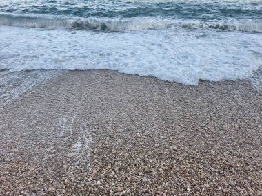 A scenic view of gentle waves washing over a smooth pebbled beach, capturing natures tranquility and serenity