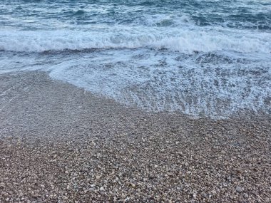 A serene beach scene with waves crashing over pebbles, evoking calmness and showcasing natural beauty