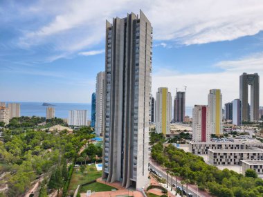 A breathtakingly stunning view of a contemporary skyscraper nestled beside lush greenery and the vast ocean