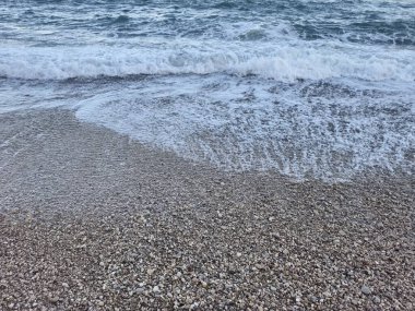 A serene beach scene with waves crashing over pebbles, evoking calmness and showcasing natural beauty