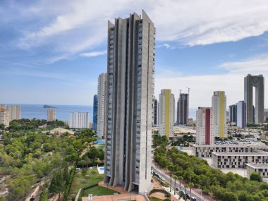 A breathtakingly stunning view of a contemporary skyscraper nestled beside lush greenery and the vast ocean