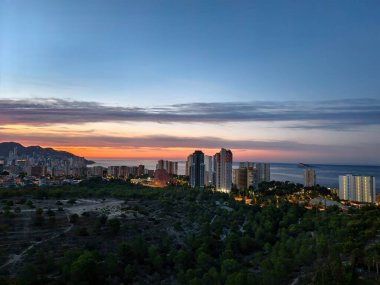 Experience the stunning beauty of a sunset with vibrant hues over a coastal city and its impressive skyline