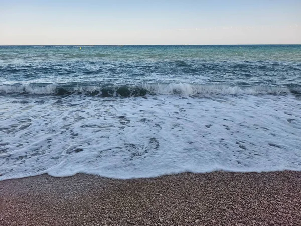 Gentle waves are lapping softly at the shore, creating a serene and tranquil seaside atmosphere that enchants