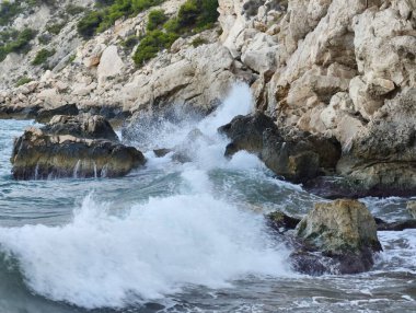 Dinamik ve güçlü deniz dalgaları çarpışıyor çarpıcı bir kıyı manzarasında engebeli kayalıklarla.
