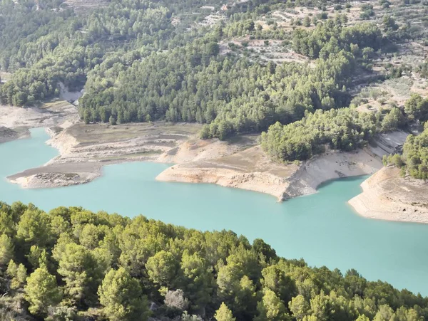 A stunning and picturesque view of a beautiful turquoise reservoir surrounded by lush, vibrant green trees