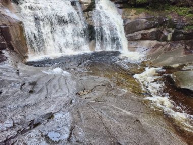 A stunning waterfall cascades over smooth rocks, creating a serene and peaceful atmosphere in natures embrace