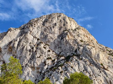 Mavi arkaplanı olan kayalık bir dağ.