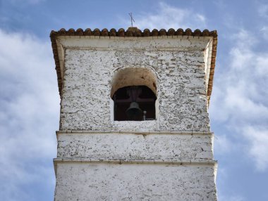 An enchanting and charming bell tower with a rustic look framed beautifully against a bright clear blue sky
