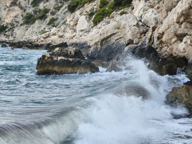 Güçlü okyanus dalgaları engebeli kayalıklara çarpar. Doğanın çarpıcı güzelliğini ve muazzam gücünü sergiler.