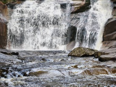 A breathtakingly stunning waterfall gracefully cascading over large rocks in a serene, natural setting