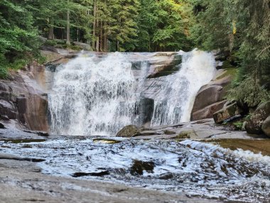 A breathtaking waterfall gracefully cascading over rugged rocks, creating a beautifully peaceful natural scene