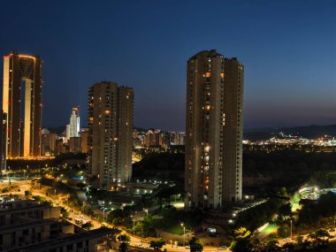 Güzel bir şehir silueti geceye dönüşüyor, modern mimari ve canlı ışıklar sergiliyor..