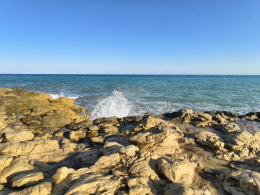 Dalgalar kıyıya vurur, güçlü okyanus dalgaları acımasız bir şekilde engebeli kıyı şeridini vurur.