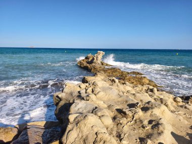 Uçurum denizle buluşur, manzaralı kireç taşı mavi gökyüzünün altında huzurlu turkuaz denize doğru uzanır.