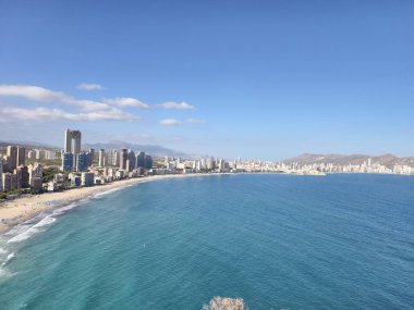 Çarpıcı turkuaz körfez manzarası, yumuşak dalgalar ve uzak kulelerin yer aldığı cennet turkuaz körfez.