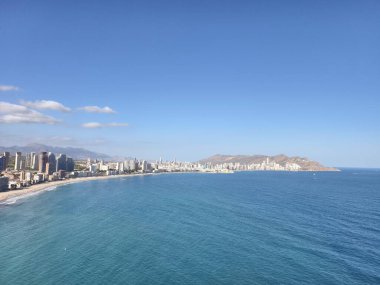 Huzurlu okyanus ve şehir manzarası, sakin bir sabah, sakin bir deniz kenarı ve arka planda şehir silüeti.