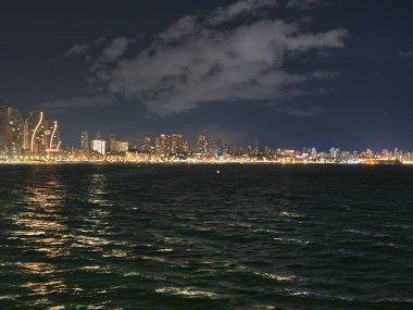 tenha okyanus manzarası, engin gece deniz manzarası ufuk boyunca parlayan uzak bir şehir.