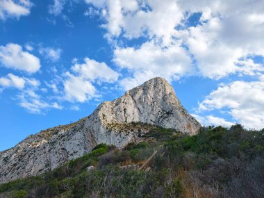 Güneşli tepe sahnesi, parlak güneş bulutlu zeminin altındaki kireçtaşı sırtı aydınlatıyor.