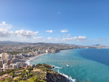 Sahil ufuk çizgisi manzarası, deniz kıyısındaki hareketli tatil beldesi, canlı sahil manzarası plajları ve tepeleri olan.
