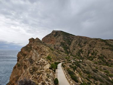 Manzaralı sahil yolu, dolambaçlı sahil yolu kayalık uçurumlar ve bulutlu ufuklar altında uzak ufukların görüntüsü.
