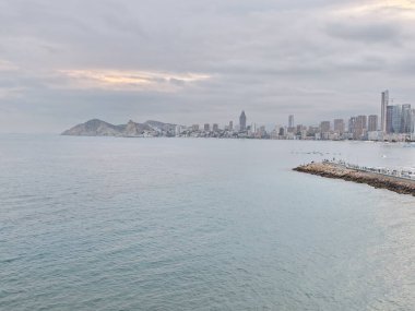 Sakin sahil manzarası, sakin kıyı manzarası bulutlu gökyüzü ve turkuaz altında şehir manzarası