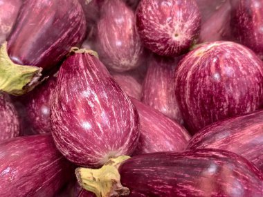 Yakın plan görüntü canlı mor patlıcanları, desenli ciltleri ve yeşil gövdeleri yakalıyor.