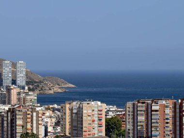Okyanus kıyısındaki modern ufuk çizgisi, yüksek binalar ve mavi suların yer aldığı kıyı metropol alanı