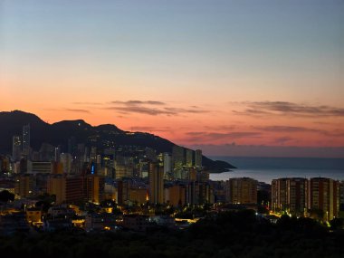 Deniz kenarı manzarasında sakin bir alacakaranlık, yumuşak pembe ve turuncu renkler battaniye liman silueti sahnesi