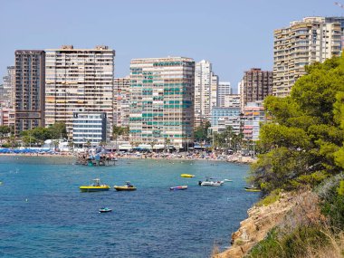 Huzurlu sahil manzarası, sakin deniz manzarası şehir manzarası, kayık ve ağaçların bulunduğu huzurlu kıyı manzarası.