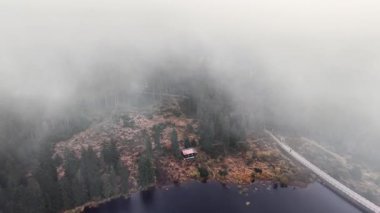 Sisli kıyı şeridi boyunca yuva yapmış uzak bir kulübe, izolasyon inzivası, dolambaçlı erişim ve sisli