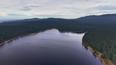 Uzak dağ sırtları ile yansıtıcı göl sahnesi, geniş sakin göl bereketli orman ve uzak dağ
