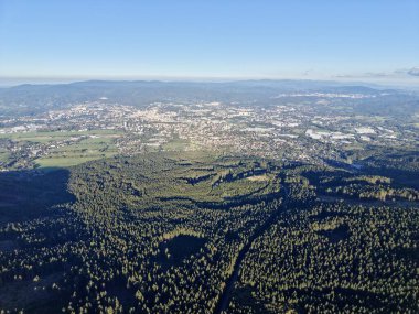 Orman tepe örtüsü uzak şehir manzarasını ve dolambaçlı vadileri aydınlık, berrak gökyüzü gölgelerini ortaya çıkarıyor.