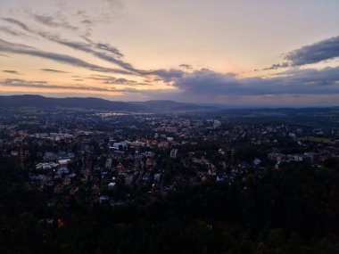 Sıcak Renk Gradyanı, Siluetli Tepeleri olan, Dramatik Bulut Altında Günbatımı Hava Görüntüleme Kasabası
