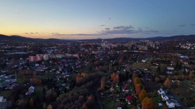 Gün batımı sessiz bir banliyöyü aydınlatıyor, sakin bir akşam manzarası parlayan sokaklar ve uzak bir ufuk çizgisi