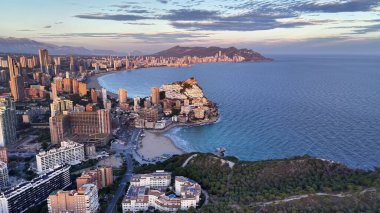 Şafak vakti sahil kenarındaki hava muhitinde yumuşak pastel gökyüzü plajların üzerinde apartmanlar ve yeşil promontuar.